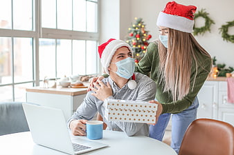Couple in Santa Hats and Face Masks Celebrating Christmas with Gift