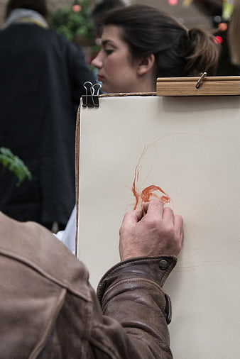 Close-up of artist sketching with red chalk on paper