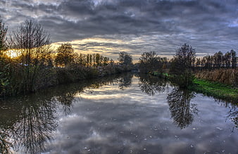 Dramatic sunset reflection on calm river with autumn trees