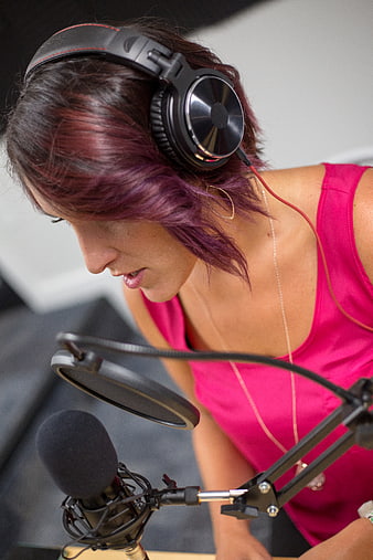 Woman with purple hair recording vocals in studio