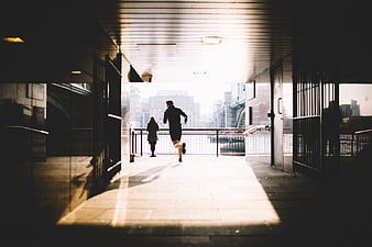 Man Running Through Urban Tunnel Towards City Skyline