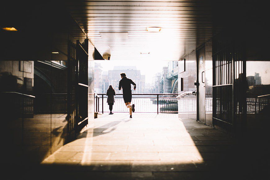 Man Running Through Urban Tunnel Towards City Skyline