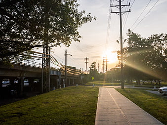 Sunset over sidewalk near train tracks and power lines