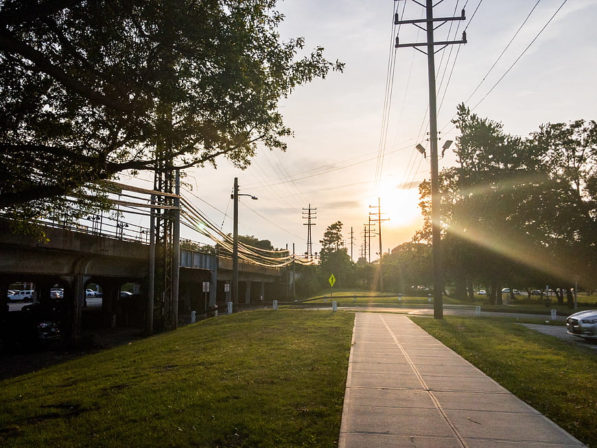 Sunset over sidewalk near train tracks and power lines