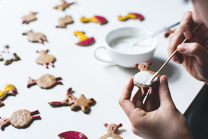 Hands decorating Easter bunny gingerbread cookies with white icing