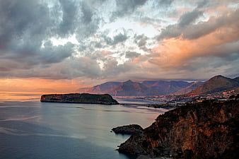 Dramatic Sunset Sky Over Coastal Landscape and Mountains