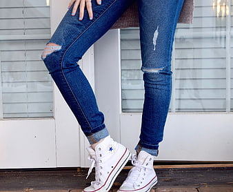 Woman wearing ripped blue jeans and white high-top sneakers
