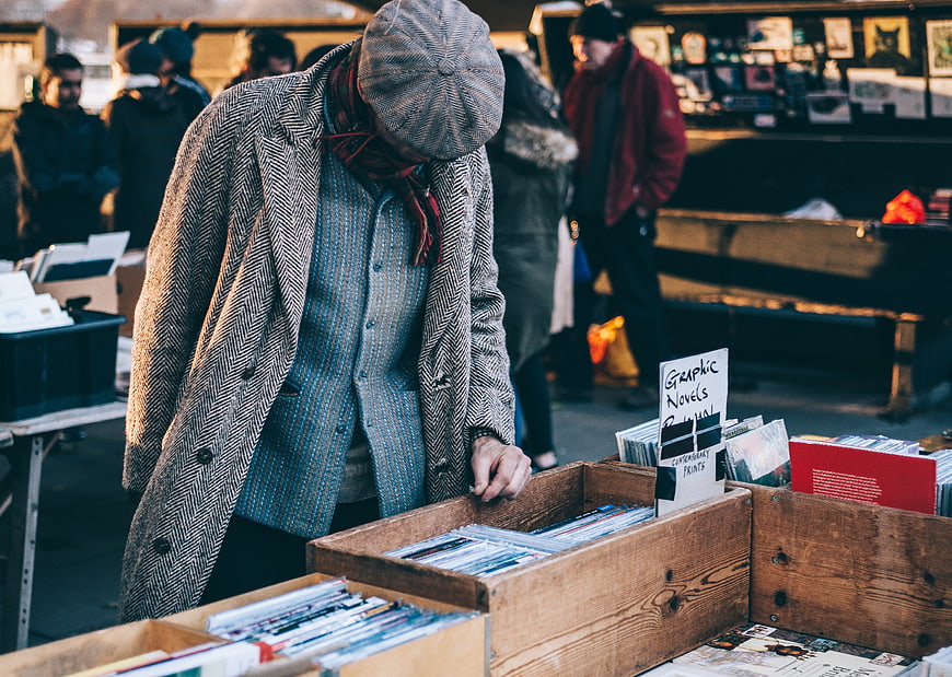 Man browsing graphic novels at outdoor market stall