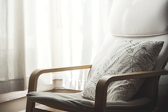 Cozy wooden armchair with leaf-patterned pillow by window