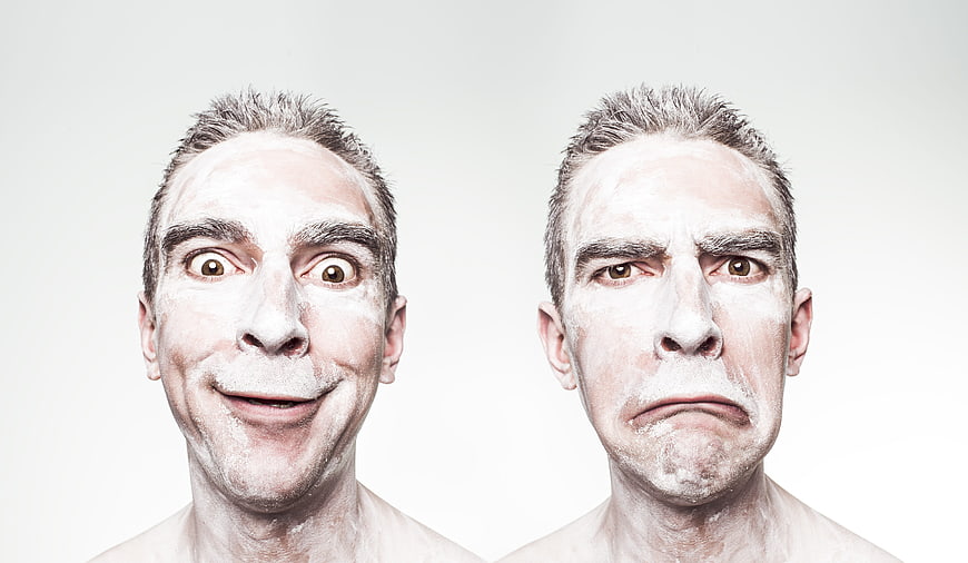 Man with white face paint showing happy and sad expressions