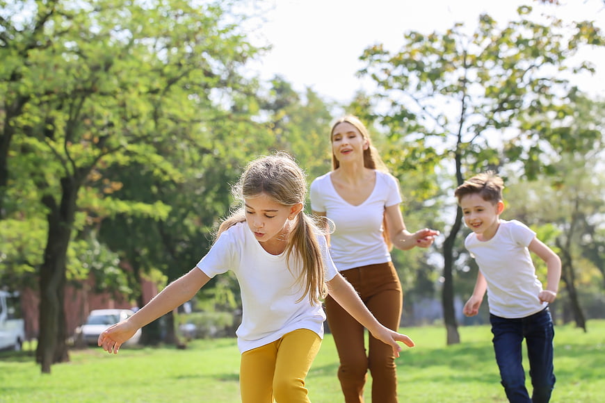 Happy family running and playing in a sunny park