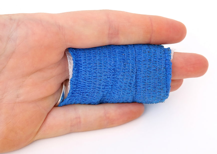 Hand holding blue medical mesh bandage roll on white background