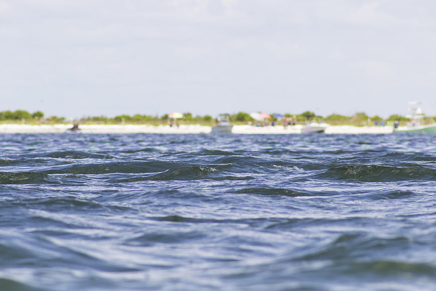 Close-up of rippling blue ocean water with blurred beach background
