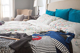 Clothes on hangers scattered on a bed with floral bedding