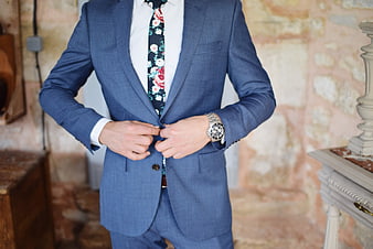 Man in Blue Suit Buttoning Jacket with Floral Tie