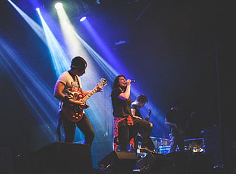 Rock band performing live on stage with blue spotlights