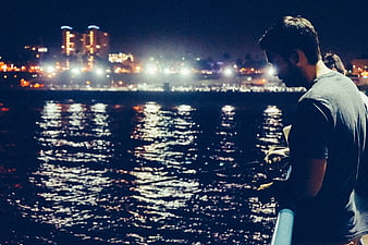 Man Fishing at Night with City Lights Reflection