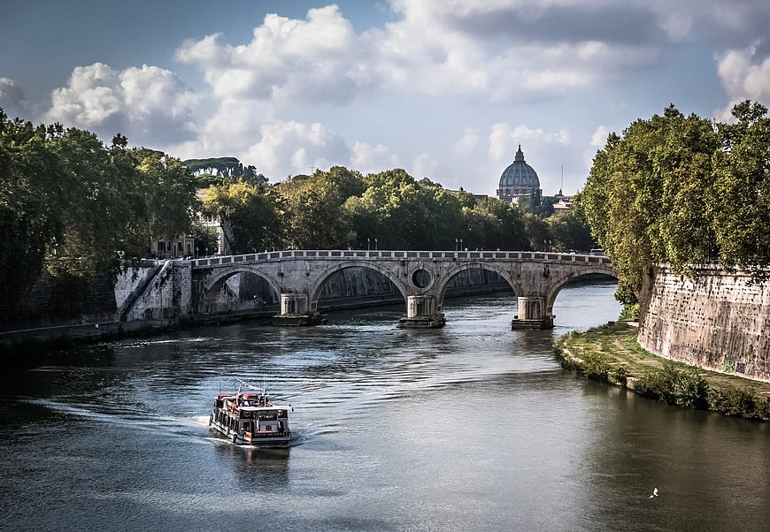 Tourist boat on Tiber River with St. Peter's Basilica dome in Rome