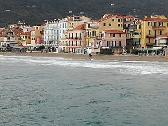 Colorful coastal town buildings along sandy beach in Liguria, Italy