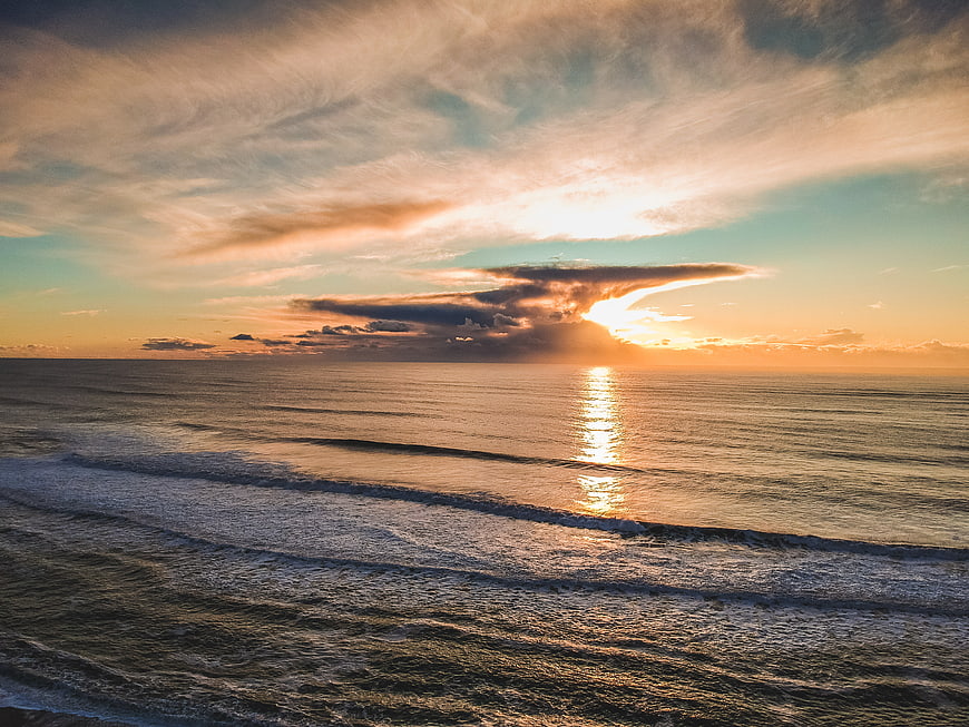 Golden Sunset Over Ocean With Dramatic Clouds and Waves