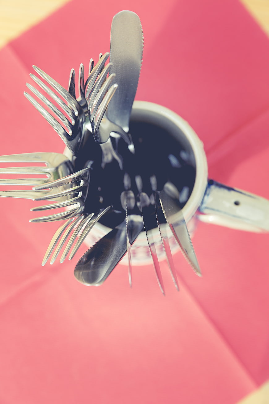 Top View of Silverware in Mug on Pink Background