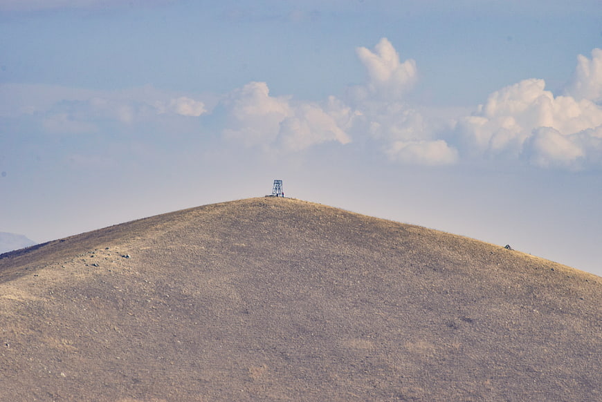 Lone communication tower on a dry grassy hilltop