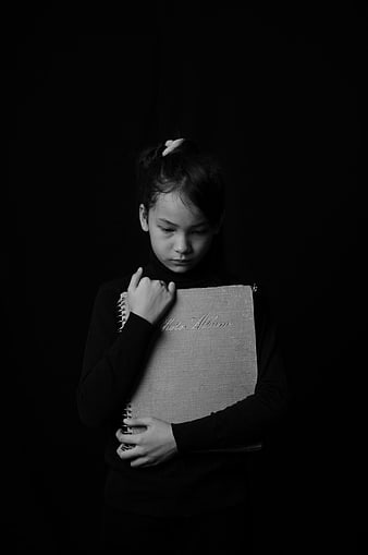 Black and white portrait of a young girl holding a photo album