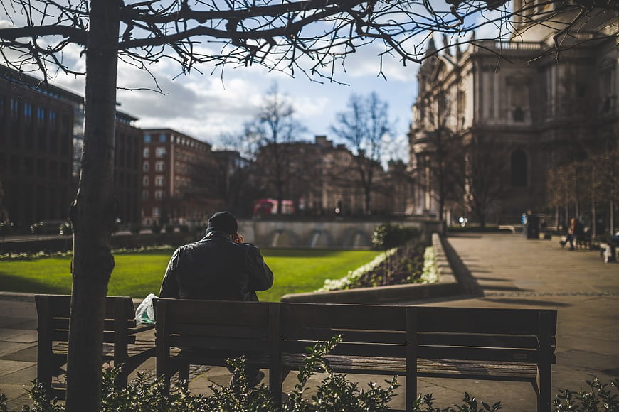 Man Sitting on Park Bench with Cathedral Background