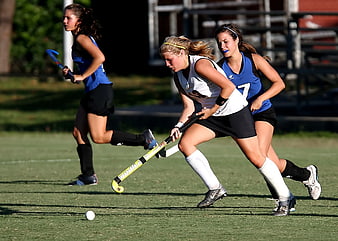Female Field Hockey Players Competing on Green Turf
