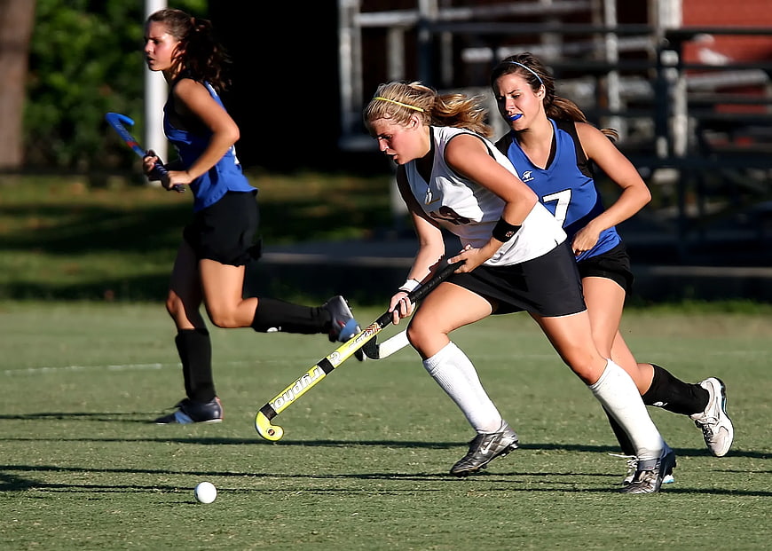 Female Field Hockey Players Competing on Green Turf