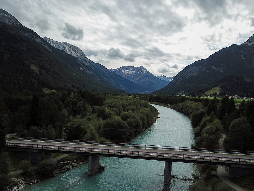 Scenic Alpine River Valley with Bridge and Mountains