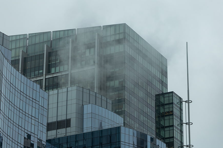 Modern glass office building shrouded in thick urban fog