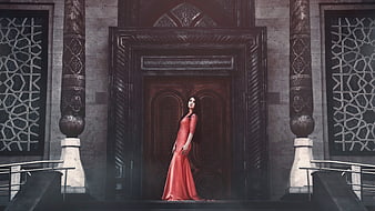 Woman in Red Dress Standing Before Ornate Wooden Door