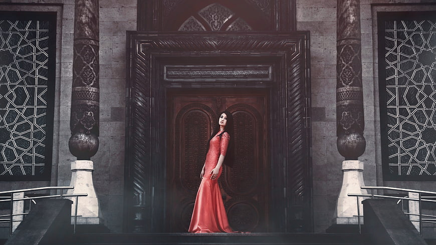 Woman in Red Dress Standing Before Ornate Wooden Door