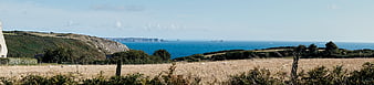 Panoramic coastal landscape with dry field and blue sea