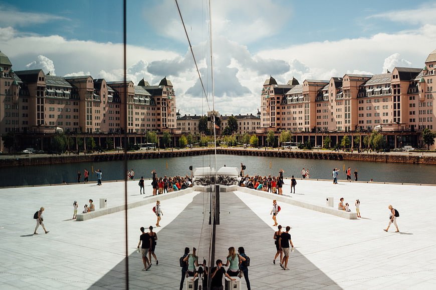 Wide angle view of Oslo Opera House roof with tourists and city skyline