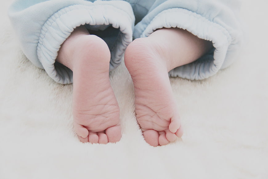 Close-up of newborn baby feet in blue pajamas
