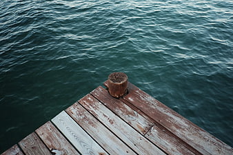 Wooden pier corner overlooking dark green rippling sea water