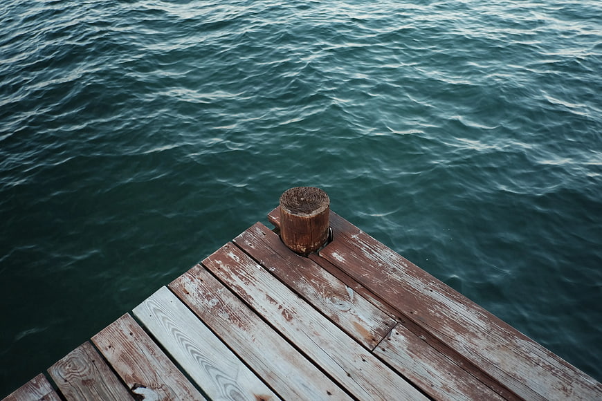 Wooden pier corner overlooking dark green rippling sea water
