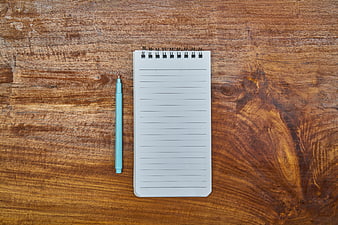 Top View of Blue Pen and Notepad on Wooden Table