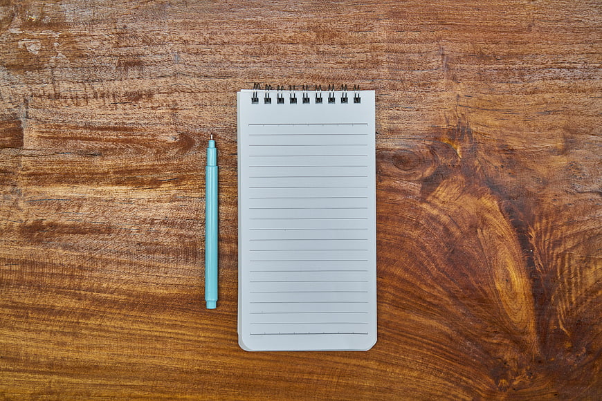 Top View of Blue Pen and Notepad on Wooden Table