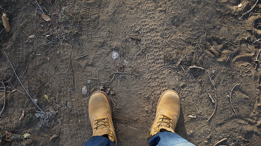 Top-down view of tan hiking boots on sandy trail