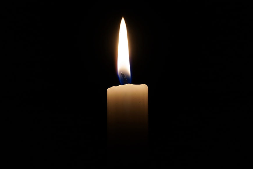 Single burning candle flame on black background