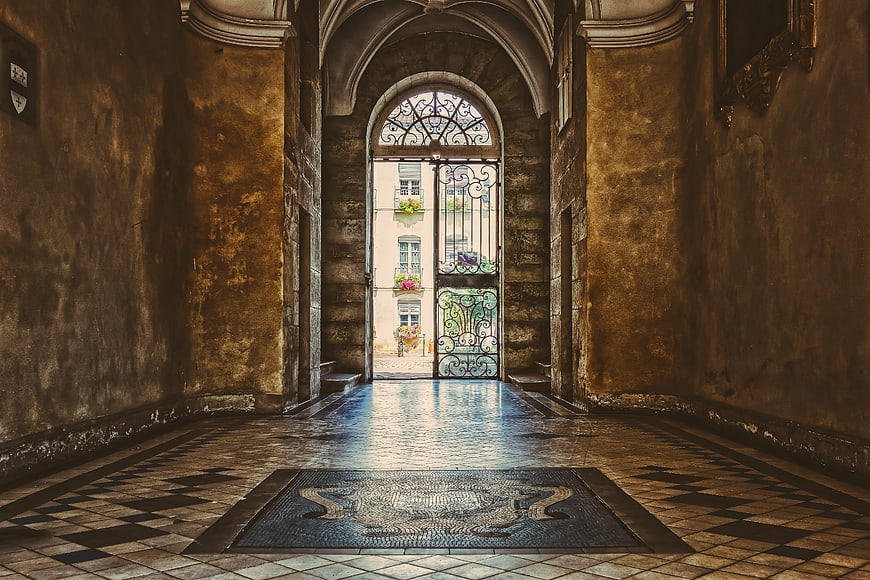Historic European Hallway With Ornate Iron Gate And Mosaic Floor