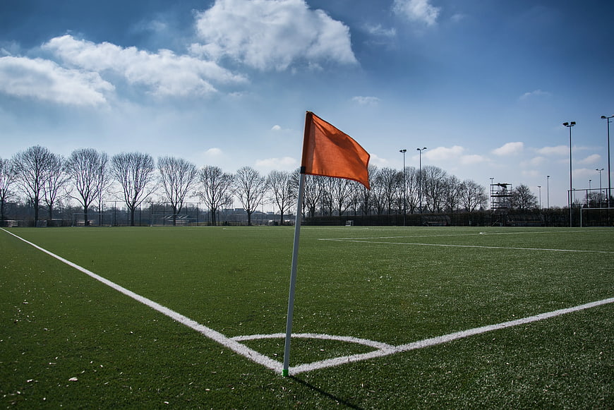 Orange corner flag on green soccer field