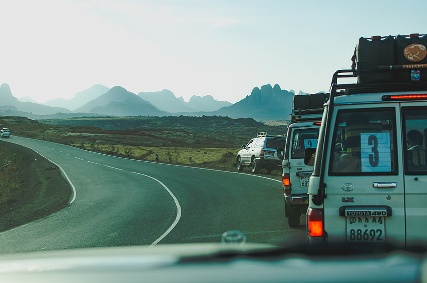 Safari convoy driving on winding road with mountains