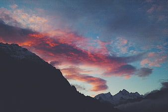 Dramatic sunset over snow-capped mountain peaks with colorful clouds