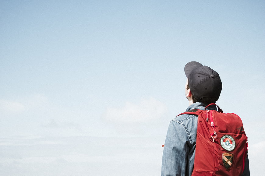 Man with Red Backpack Looking at Sky