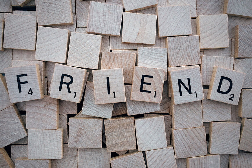 Scrabble tiles spelling the word FRIEND on a background of wooden letter cubes