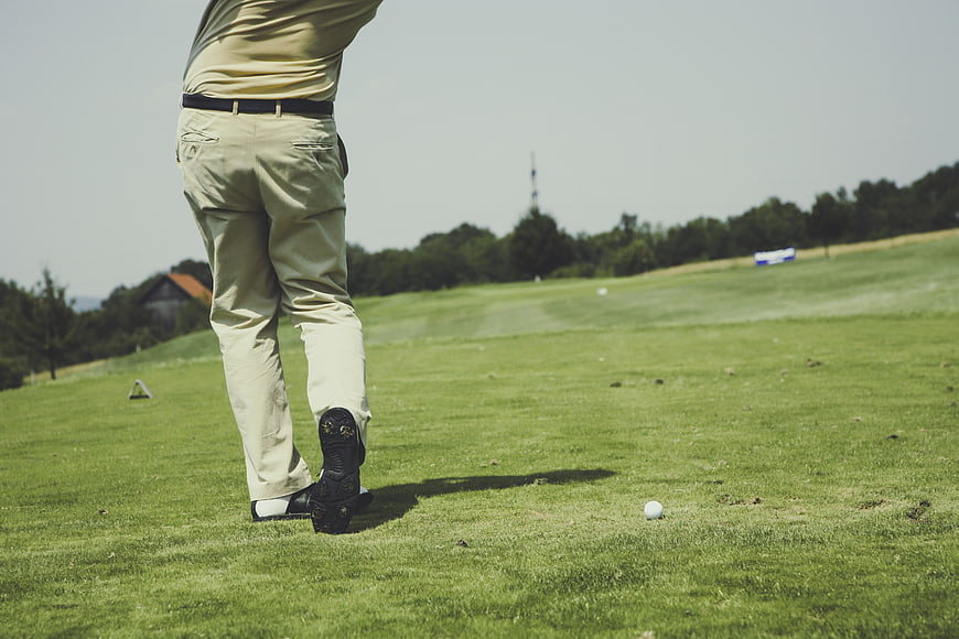 Golfer's legs and golf ball on green grass